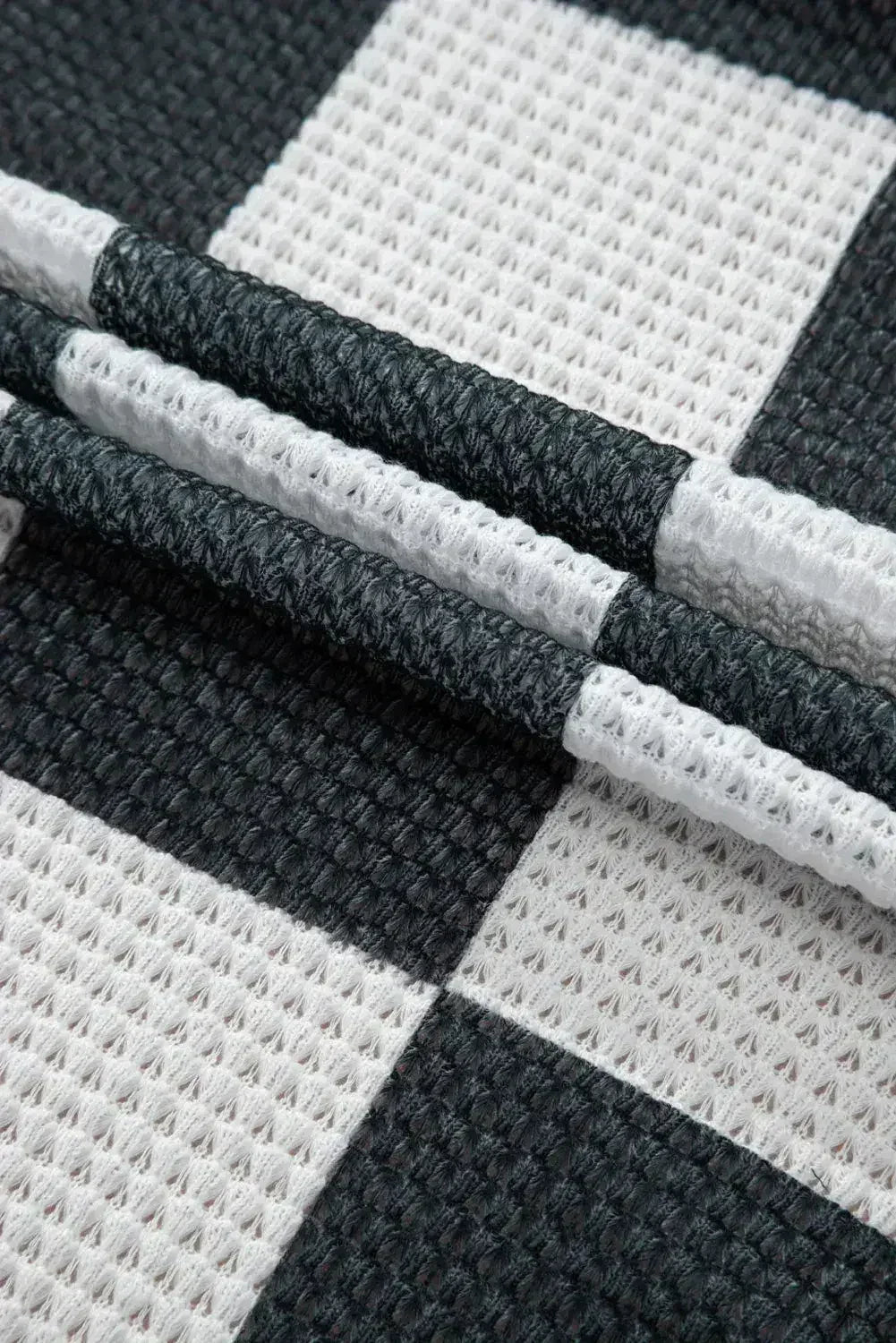 Cardigan ouvert en maille gaufrée à carreaux noirs avec trous pour les pouces