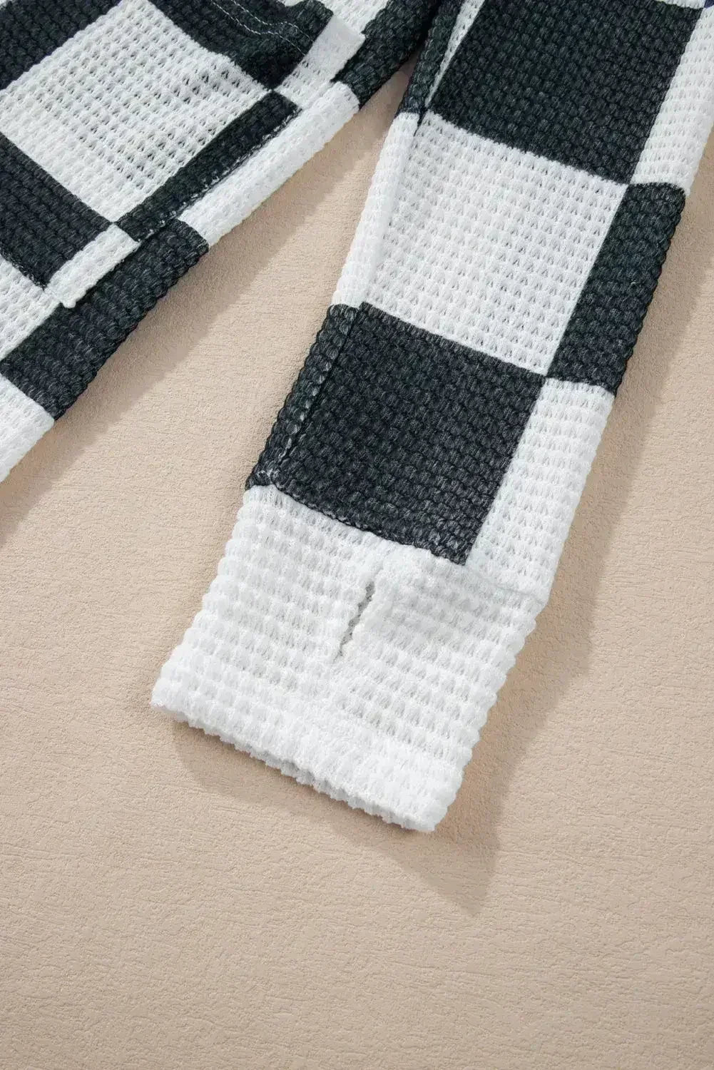 Cardigan ouvert en maille gaufrée à carreaux noirs avec trous pour les pouces