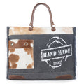 Sac de voyage Myra Dakota Trail en cuir et poils de vachette – Toile imprimée artisanale avec franges rustiques sur les côtés et anses en cuir