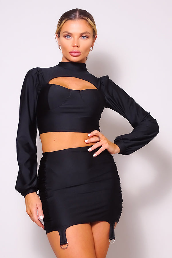 Ensemble blouse à col roulé et découpe sur le devant, manches longues bouffantes, et mini-jupe à volants froncée sur les côtés.