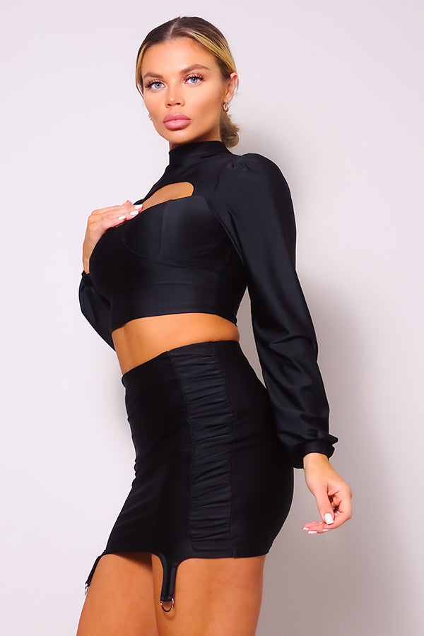 Ensemble blouse à col roulé et découpe sur le devant, manches longues bouffantes, et mini-jupe à volants froncée sur les côtés.