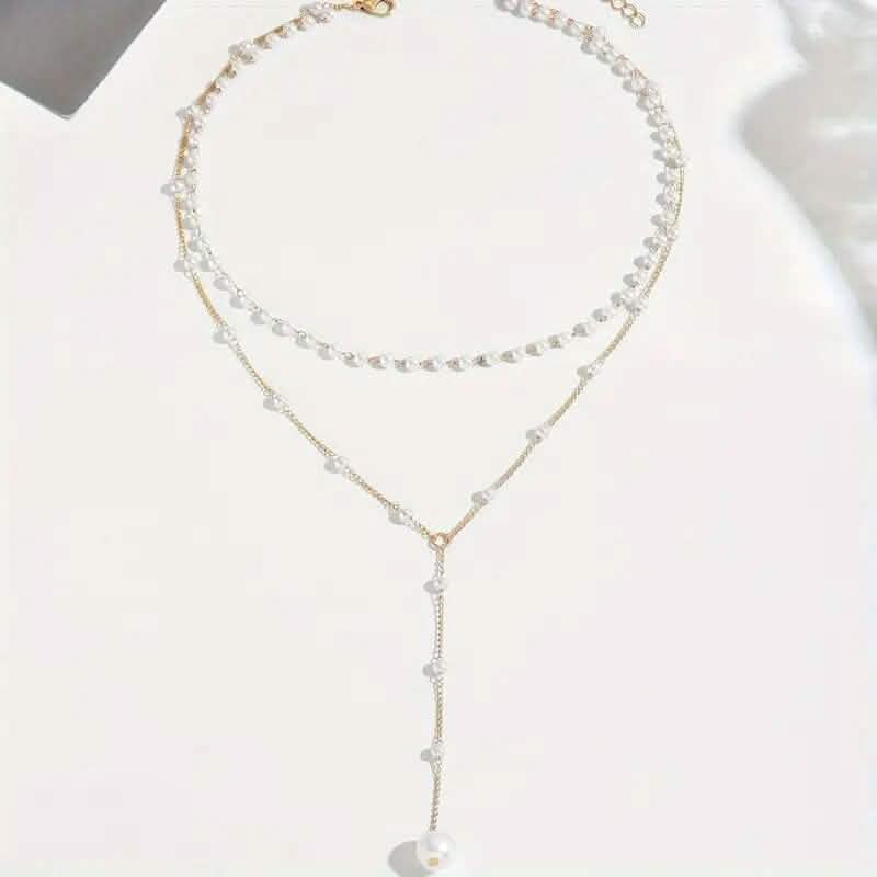 Élégant collier pendentif double couche de style vintage avec des accents de perles d'imitation et un pompon.