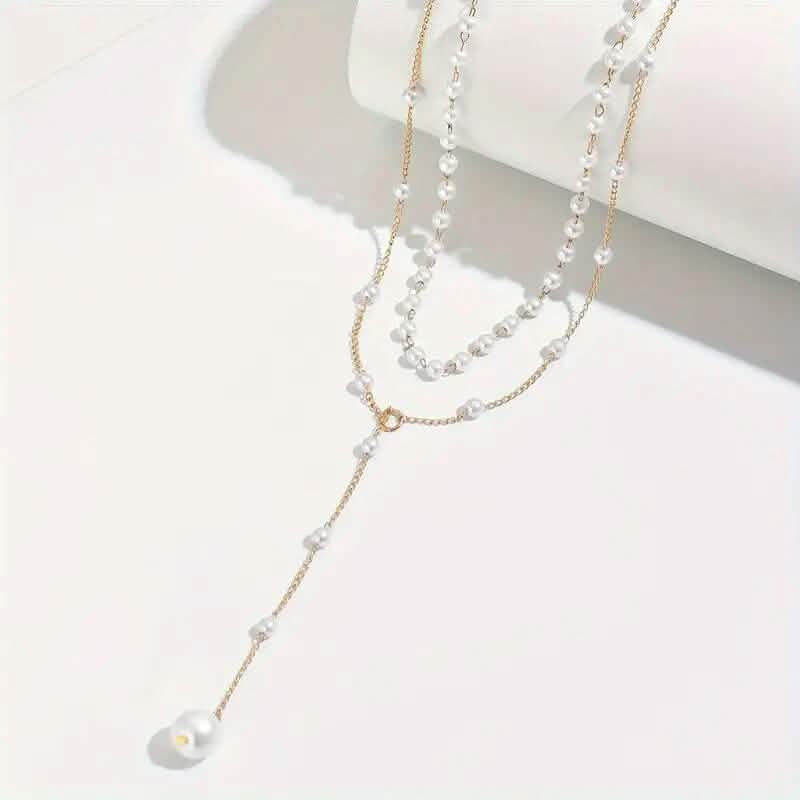 Élégant collier pendentif double couche de style vintage avec des accents de perles d'imitation et un pompon.